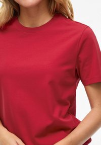 T-shirt rossa a maniche corte realizzata in cotone liscio, con scollatura a girocollo e vestibilità regolare. Design semplice, senza motivi o dettagli visibili.