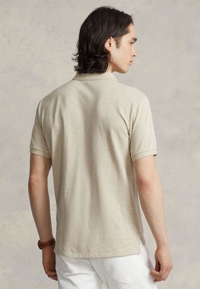 Béžové polotričko s krátkymi rukávmi, materiál z bavlnenej zmesi, bočné rozparky pre pohodlie, rovný pletený golier, bez viditeľných vzorov alebo grafiky.