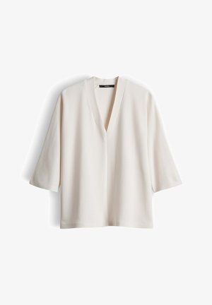 Elfenbeinfarbene V-Ausschnitt-Bluse mit langen Ärmeln, lockerem Schnitt und schlichtem Design, vor weißem Hintergrund dargestellt.