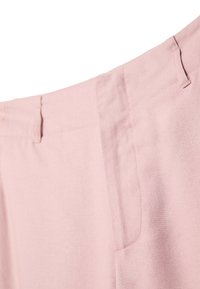 Pantalon rose clair avec taille visible, passants de ceinture et poche latérale sur fond blanc.