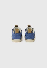 Baskets en suede bleu avec des accents beiges, forme arrondie et doublure en textile. Dotées d'une languette à l'arrière pour un enfilage facile et d'une semelle texturée.