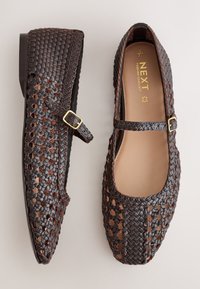 Dark brown woven Mary Jane flats with a small buckle strap and tan insole branded "NEXT Forever Comfort" shown from top and side views.
