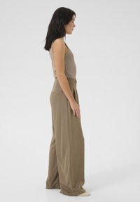 Beige sleeveless top paired with light brown wide-leg trousers. The fabric appears smooth with a tailored fit, featuring a back pocket.