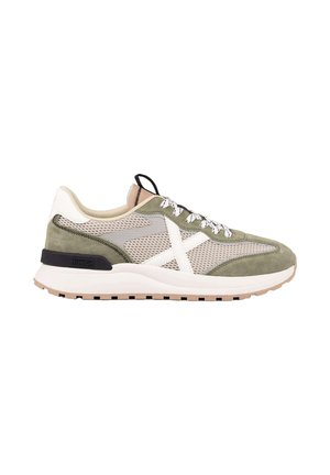 Zapatilla deportiva de malla verde claro y beige con cordones blancos, detalle cruzado blanco en el lateral y una suela blanca gruesa con un detalle negro en el talón.