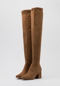 Brown suede over-the-knee boots with a square toe and block heel. Smooth texture and seamless design.