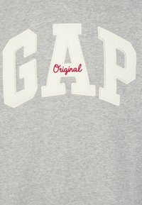Felpa grigia con grande lettering bianco "GAP" e un piccolo testo rosso "Original", realizzata in un morbido tessuto testurizzato.