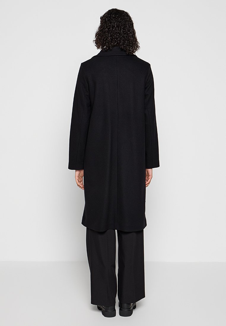 Langer schwarzer Mantel mit geradem Design, Seitentaschen und Kragen. Aus dickem Stoff gefertigt, mit glatter Textur und minimalen Details.