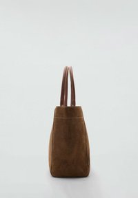 Sac fourre-tout en daim marron avec deux poignées en cuir arrondies, forme rectangulaire verticale et couture blanche visible sur un fond clair.