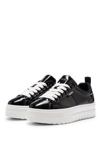 Schwarze Lack- und Leder-Sneaker mit einer dicken weißen Sohle. Verfügt über weiße Schnürsenkel, Logo-Akzente und eine Zuglasche an der Ferse.