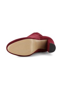 Bottine en suede rouge à bout pointu, texture lisse et talon empilé ; la semelle en caoutchouc présente un léger relief pour une meilleure adhérence.