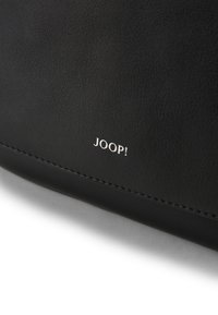 Borsa in pelle nera con bordi cuciti e logo argentato "JOOP!" impresso sul davanti. Texture liscia, forma rettangolare.