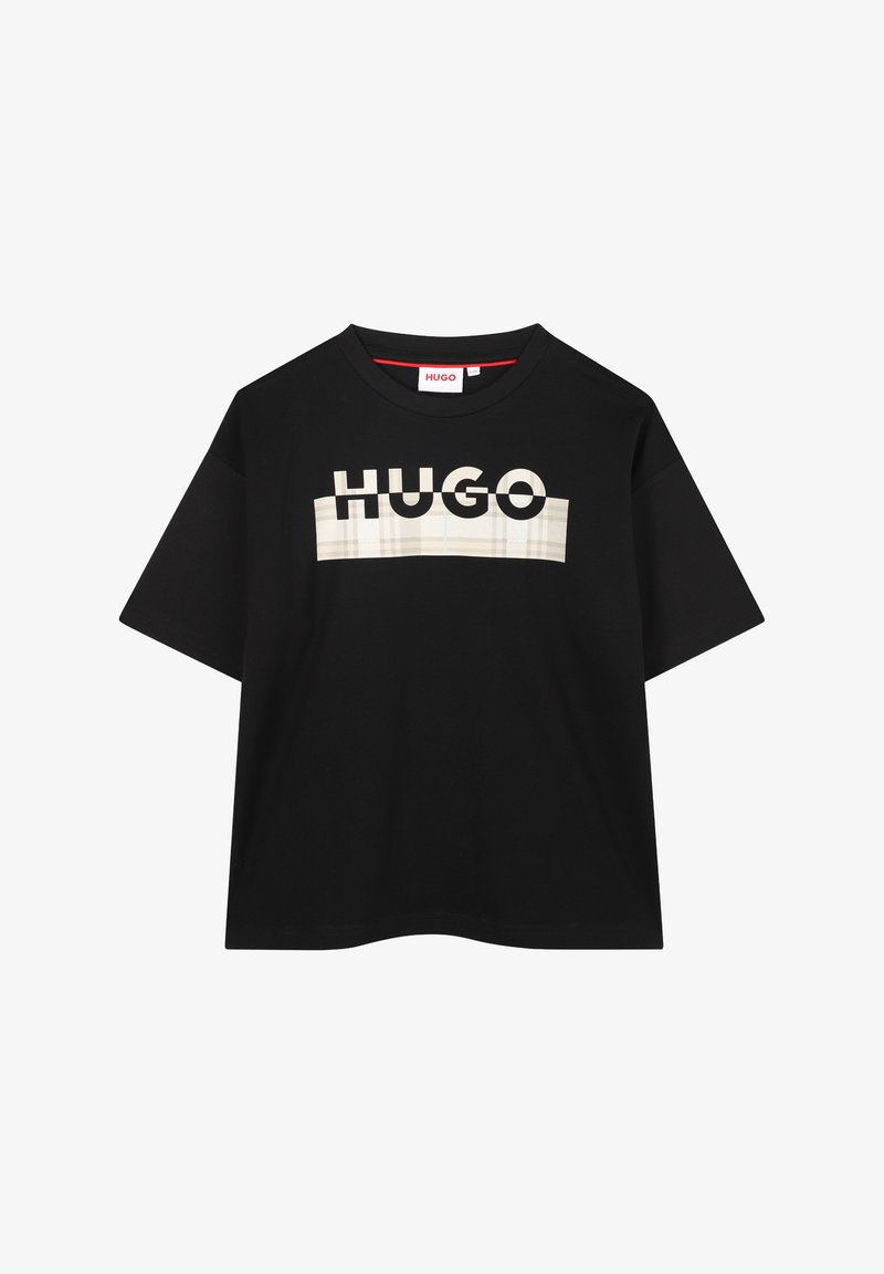 T-shirt noir avec un logo "HUGO" audacieux et contrasté en blanc et beige. Manches courtes avec un col rond. Texture de tissu lisse.