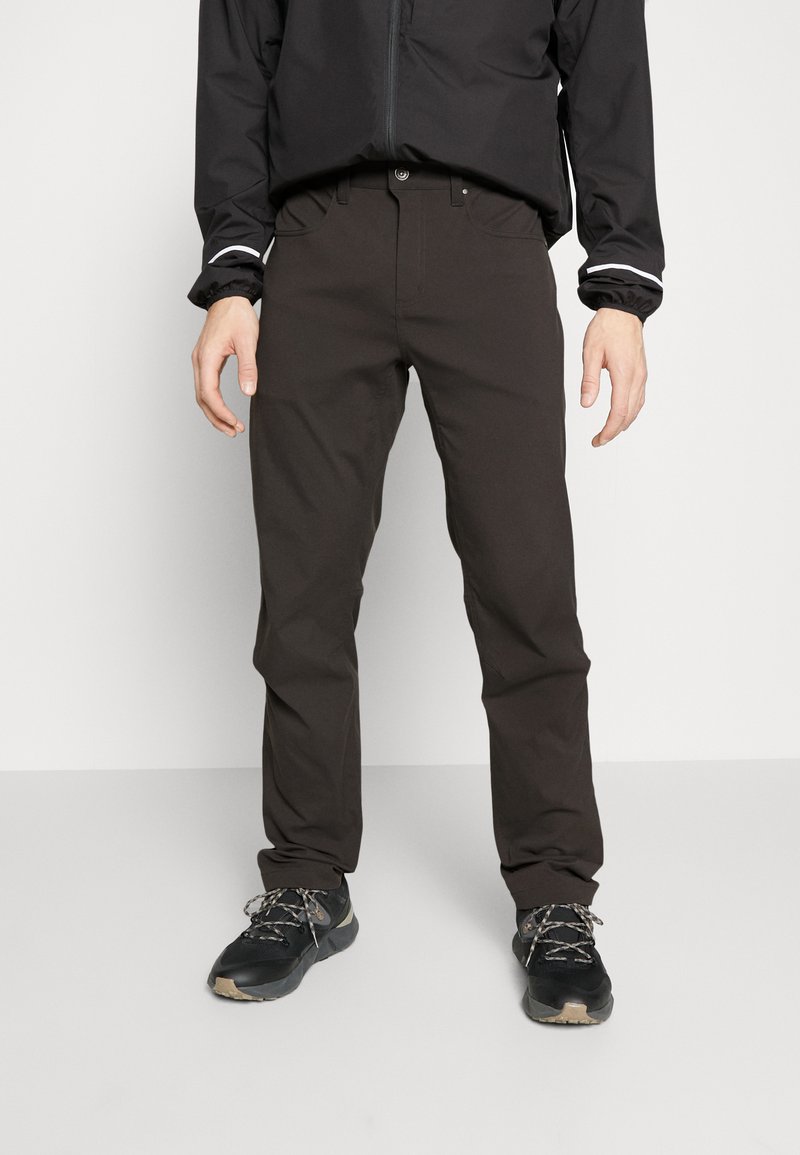 Tamno smeđe hlače uskog kroja, izrađene od rastezljivog materijala. Imaju četiri džepa i standardni pojas s petljama za remen.