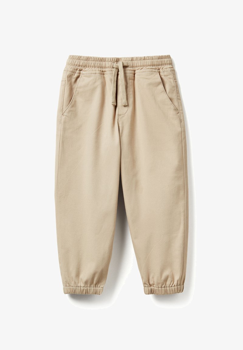 Béžové bavlněné teplákové kalhoty s elastickým pasem, stahovací šňůrkou, bočními kapsami a elastickými manžetami u kotníků.