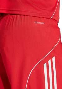Rote Sportshorts mit gerippter Textur, ausgestattet mit weißen Akzenten und drei vertikalen Streifen an der Seite. Unten am Bund mit "AEROREADY" gekennzeichnet.