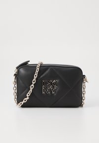 Svart kviltad läder crossbody-väska med en silverkedjesnodd och en framträdande DKNY-logotyp på framsidan. Slät textur med diamantmönster.