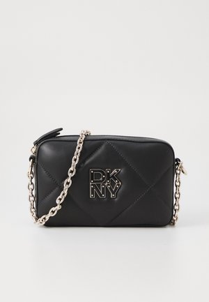 Black quilted leather crossbody bag with a silver chain strap and prominent DKNY logo on the front. Smooth texture with diamond patterns.