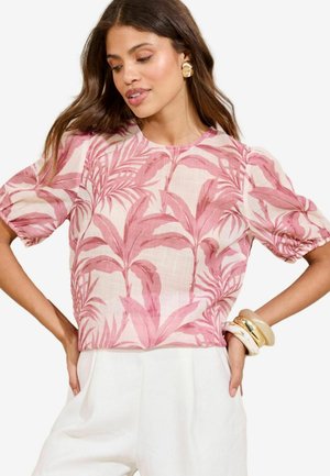 Roze en crèmekleurige blouse met een botanische print, voorzien van korte pofmouwen en een ronde halslijn, gecombineerd met witte broek.