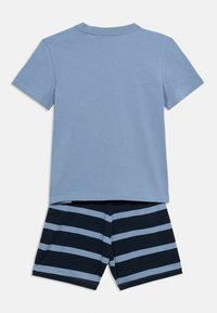 Ανοιχτό μπλε κοντομάνικο T-shirt συνδυασμένο με σκούρο μπλε σορτς με ρίγες. Μαλακό βαμβακερό ύφασμα, άνετη γραμμή, επίπεδα ραφές και απλός σχεδιασμός.