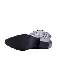 Bota negra de tacón con un upper texturizado y una suela de goma lisa. Presenta una punta afilada y un tacón estriado para mayor agarre.