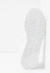 Semelle blanche de basket avec un motif de bande de roulement texturé ondulé, affichant un logo "asics" au centre, sur un fond blanc uni.