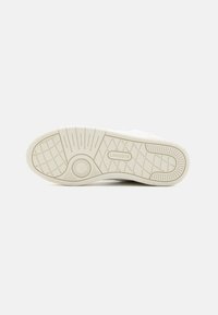 Hvit sneakersåle med teksturert gummi, med geometrisk mønster og logo. Myk, fleksibel materiale for grep og komfort.