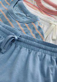Ensemble décontracté avec shorts bleus à taille élastique et hauts à manches courtes rayés dans des tons bleus et roses, posés à plat.