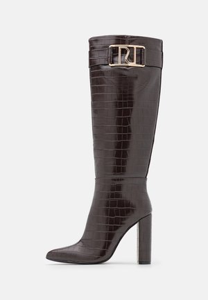Botte haute en cuir brun foncé au motif crocodile, avec un talon bloc élevé et une sangle dorée bouclée près du sommet.