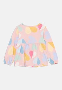 Langermet topp i rosa bomull, med peplum-design, og flerfargede hjertemønstre i pastellfarger. Rund hals og innsamlede mansjetter.