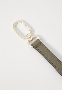 Bretelle en cuir vert olive avec une texture lisse, dotée d'un clip en métal doré et de détails de couture le long des bords.