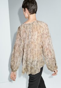 Durchsichtige, beige Bluse mit langen Ärmeln und einem strukturierten Muster aus vertikalen Linien und Punkten. Leichter Stoff, lockere Passform, runder Halsauschnitt.