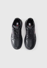 Black leather sneakers with a rounded toe, flat lace-up design, perforated details, and branded insole featuring red and blue accents.