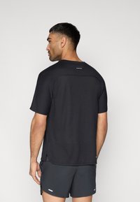 Μαύρο αθλητικό μπλουζάκι με στρογγυλή λαιμόκοψη, κοντά μανίκια και υφή από δίχτυ. Στην πλάτη διαθέτει λογότυπο και πλαϊνές σχισμές για αερισμό.