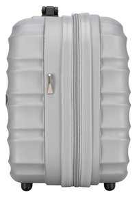 Valigia rigida grigia con finitura testurizzata, design scanalato, doppie cerniere e quattro ruote per la mobilità. Forma rettangolare compatta.