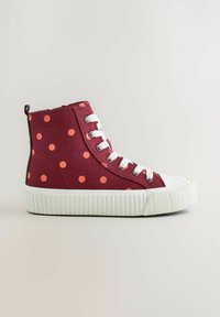 Baskets montantes bordeaux à pois orange, lacets blancs, semelle et bout en caoutchouc blanc épais sur un fond neutre.