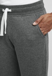 Grå sweatpants med en mjuk textur, elastisk midja och vit snörning. Har sidofickor och en avslappnad passform.