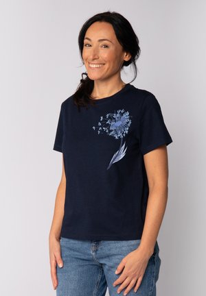 T-shirt en coton bleu marine avec des manches courtes, présentant un motif floral de pissenlit bleu clair sur le côté gauche. Coupe décontractée, encolure ronde.