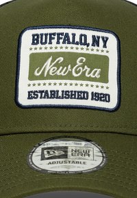 Gorra ajustable de color verde oliva con un parche bordado en blanco y azul marino que lleva las etiquetas "New Era", "Buffalo, NY" y "Establecido en 1920".