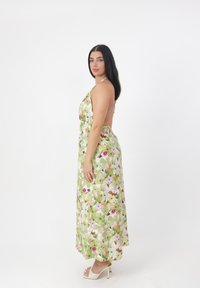 Grøn blomster maxi kjole med halterneck-design, der har pink og hvide blomster mønstre samt en let eksponering af ryggen.