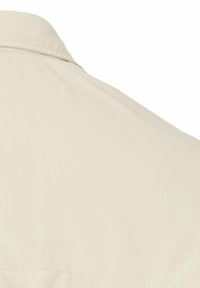Beige Baumwollhemd mit glatter Textur, Knöpfen am Kragen und schlichter Gestaltung; sichtbare Nähte entlang der Rückennaht.