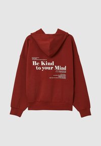 Un sweat à capuche rouge avec un grand texte blanc dans le dos, incluant la phrase "Sois gentil avec ton esprit." Matériel doux, coupe décontractée.