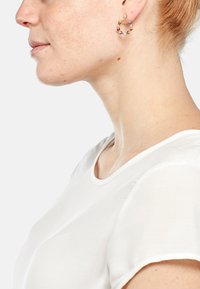 Orecchini a cerchio in oro decorati con gemme colorate, con un design circolare e superficie texturizzata. Chiusura semplice ed elegante per indossarli.