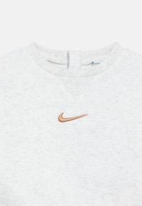 Šviesiai pilkas džemperis iš minkštos medžiagos, turintis pūstą apykaklę ir mažą, bronzinį Nike swoosh logotipą priekyje.