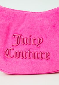Borsa in velour rosa caratterizzata da testo in rilievo "Juicy Couture" dello stesso colore, con una texture morbida e una forma arrotondata.