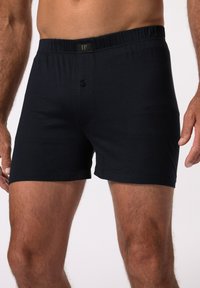 Schwarze Baumwoll-Boxershorts mit einem elastischen Bund und einer einzigen Knopfverschluss vorne. Glatte Textur, knielanges Design.