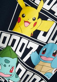 Mėlyna medvilnės marškinėliai su Pikachu, Bulbasaur ir Squirtle piešiniais. Juodas fonas su baltais tekstiniais elementais. Lygus paviršius.