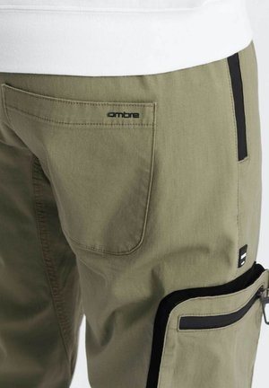 Khaki cargo bukser med en baglomme med "ombre" logo, sorte accenter på sidelommen og lynlåsen samt et struktureret stof.