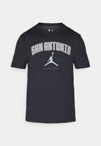 Juoda medvilninė marškinėliai su užrašu "SAN ANTONIO" įspūdingu sidabriniu šriftu, po juo esantis pilkas Air Jordan logotipas. Apvalios kaklo iškirptės dizainas.