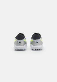Sport shoes featuring a black and silver upper with a textured design, reflective yellow accents, and white traction rubber soles.