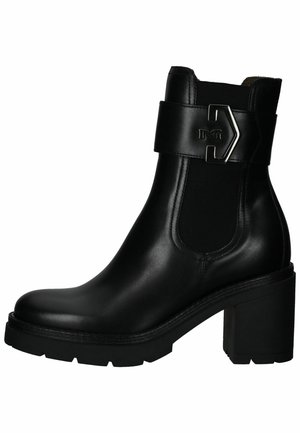 Botas de cuero negro hasta el tobillo con un tacón grueso, paneles laterales elásticos y una correa con herrajes decorativos. Textura suave con un diseño elegante.